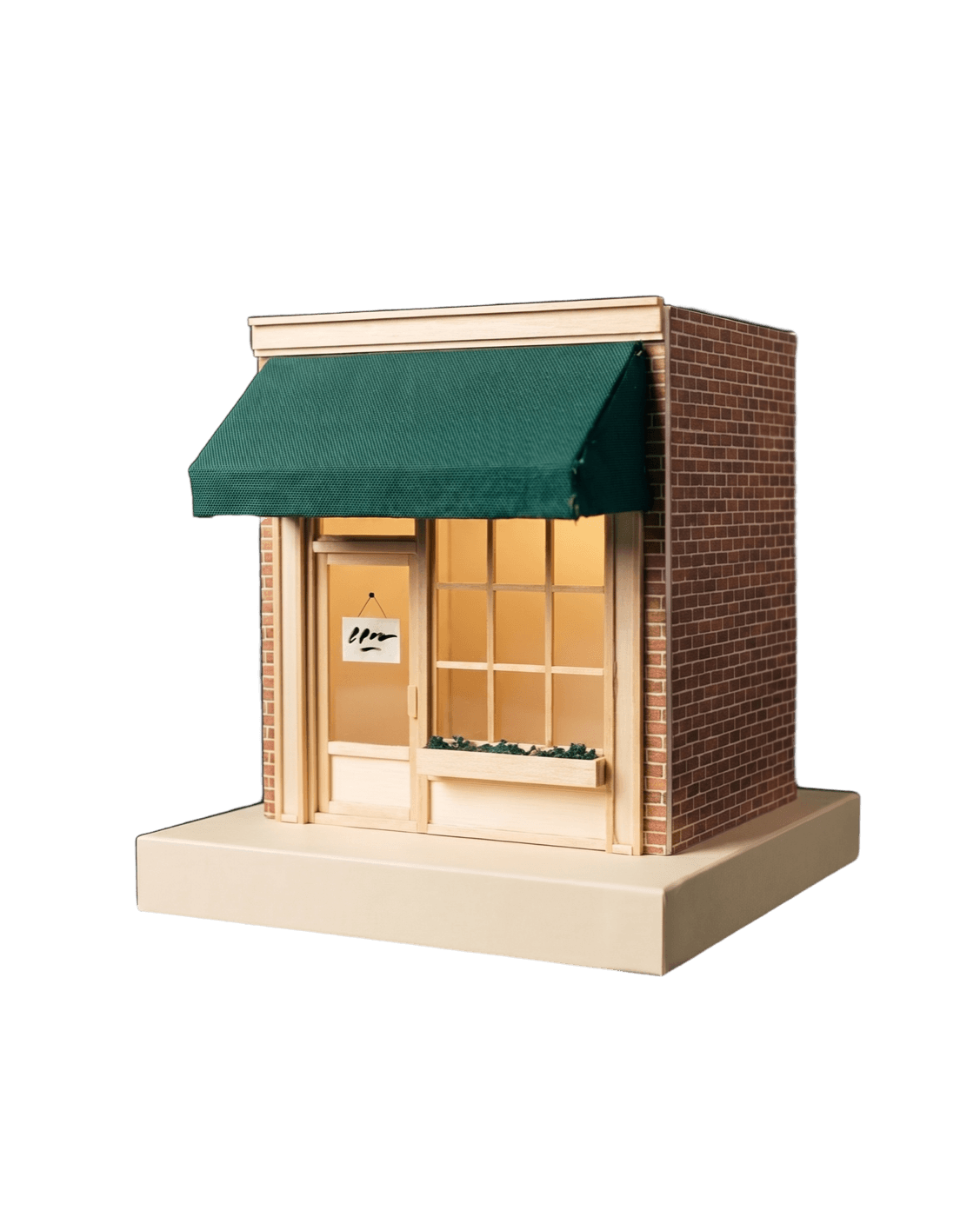 A hand-built miniature storefront model with an emerald awning, glowing from inside